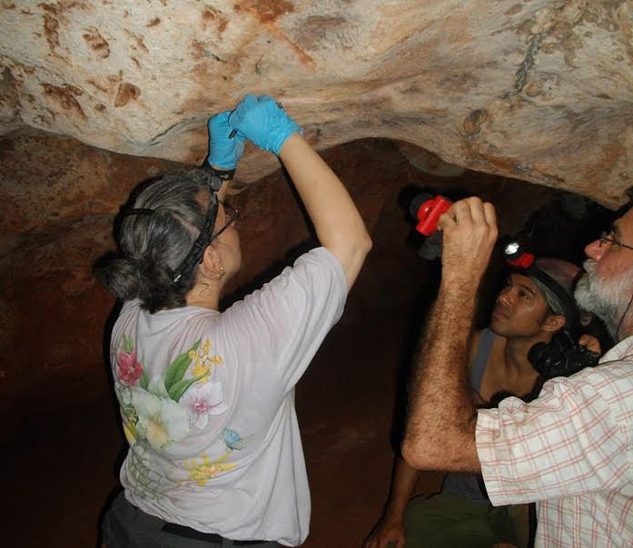 Ruth Ann Armitage (left) sampling ancient rock painting in Cuba